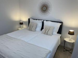 1 cama blanca con 2 almohadas y espejo en Gemütliche&Moderne Ferienwohnung Nähe Trier & Luxemburg, en Bollendorf