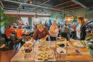 un grupo de personas sentadas en una mesa con comida en B&B Hotel De Vrije Vogel, en Elsloo