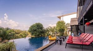a swimming pool with pink chairs and a raft in the water at Villa Nap Dau Crown Private Pool Villa Phuket in Ban Klang