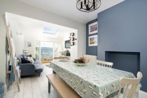 a living room with a dining room table with a blue wall at Sea View Cottage Dream By The Water in Appledore