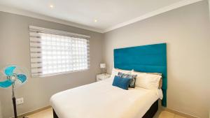 a bedroom with a large bed with a blue headboard at Midrand Air B and B House in Midrand +10 photos