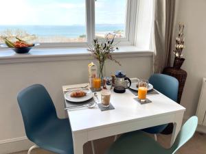 uma mesa branca com comida para o pequeno-almoço e uma janela em Sea View Family Stay by Beach Gym & Parking em Bournemouth