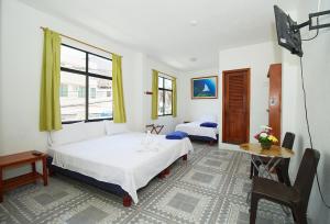 a bedroom with two beds and a table and a window at Hostal Gardner in Puerto Ayora