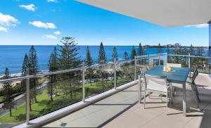 a balcony with a blue table and chairs and the ocean at Oceans Mooloolaba in Mooloolaba