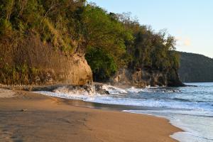 a beach with a cliff and the ocean at La Vue 2 in Anse La Raye
