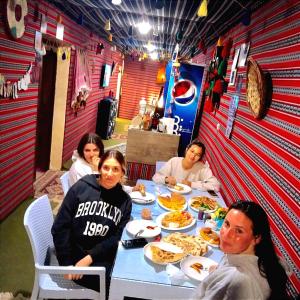 Un grupo de personas sentadas en una mesa comiendo pizza en Majido Hotel, en Wadi Musa