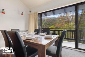 a dining room with a table and a large window at Mowamba E5 in Thredbo