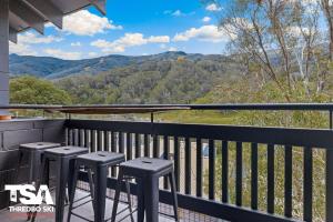a balcony with stools and a view of the mountains at Mowamba E5 in Thredbo