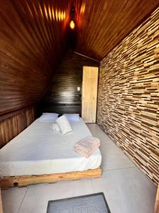 1 dormitorio con 1 cama en una pared de madera en Casa Tucan Glamping, en Turrialba
