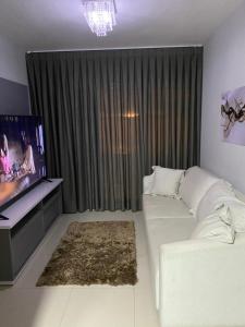 a living room with a white couch and a tv at Apartamento próximo da Lucas in Atibaia