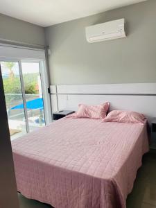 um quarto com uma cama rosa e um cobertor rosa em Apartamento próximo da Lucas em Atibaia