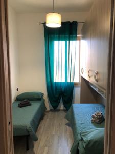 een kamer met 2 bedden en een raam met blauwe gordijnen bij Balai house in Porto Torres