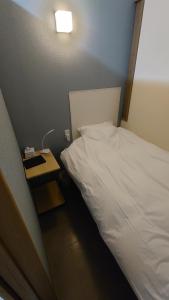a bedroom with a white bed and a night stand at 宿 inn TEK-TEK in Sanuki