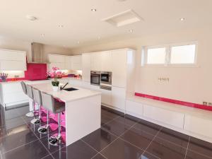 a kitchen with white cabinets and pink accents at 105 Spilsby Road in Boston