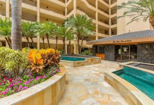 a hotel courtyard with two pools and palm trees at Polo Beach Club Two Bedrooms - Sleeps 6 by Coldwell Banker Island Vacations in Wailea