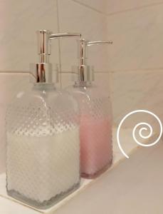 due bottiglie di vetro sedute su un lavandino del bagno di Departamento un dormitorio Ubicación ideal Córdoba a Córdoba