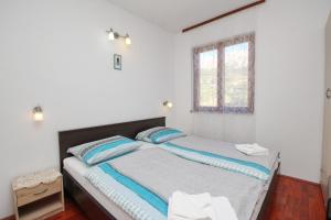 sypialnia z łóżkiem z niebieskimi poduszkami i oknem w obiekcie Apartments with parking spaces Baska, Krk - 18861 w Bašce