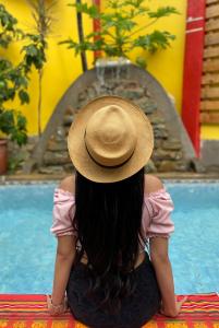 una mujer con un sombrero sentada frente a una piscina en Dreamkapture Hostel close to the airport and bus terminal, en Guayaquil