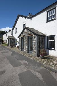 a white house with a stone building on a street at No 2 The Forge Coniston in Coniston