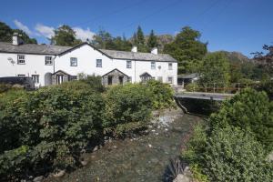 a white house with a bridge over a river at No 2 The Forge Coniston in Coniston