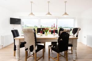mesa de comedor con sillas blancas y negras en Westwood Cottage en Longniddry