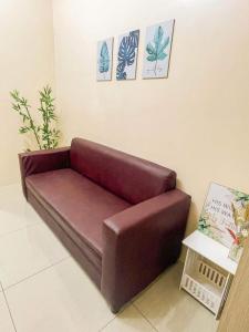 um sofá castanho sentado numa sala com cartazes na parede em Shore Residences Facing Pool em Manila