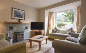 a living room with two couches and a fireplace at Netherbeck Cottage Coniston in Coniston