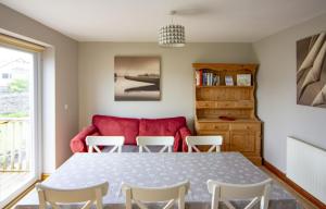 uma sala de jantar com uma mesa e cadeiras e um sofá vermelho em Netherbeck Cottage Coniston em Coniston