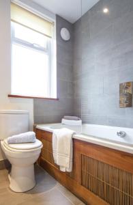 a bathroom with a tub and a toilet and a window at Netherbeck Cottage Coniston in Coniston