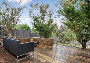 a backyard with a wooden deck with chairs and trees at Jayda in Daylesford