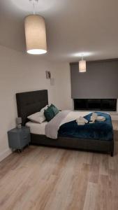 a bedroom with a large bed and a wooden floor at Modern Stylish Apartment in Birmingham in West Bromwich