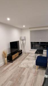 a living room with a flat screen tv and a blue couch at Modern Stylish Apartment in Birmingham in West Bromwich