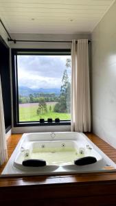 a bath tub in a room with a large window at Refúgio Serra e Flor in Urubici