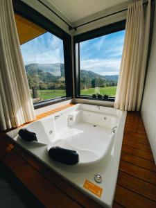 eine Badewanne in einem Zimmer mit einem großen Fenster in der Unterkunft Refúgio Serra e Flor in Urubici