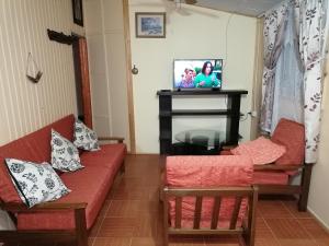 sala de estar con 2 sofás rojos y TV en Cabaña "Descanso playero" en Quintero