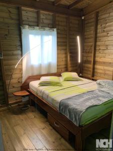a bed in a wooden room with a window at MAISON FAMILLE RANCE in Pointe-Noire