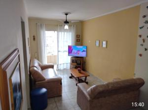a living room with two couches and a flat screen tv at Acolhedor com suíte e wi-fi in Praia Grande