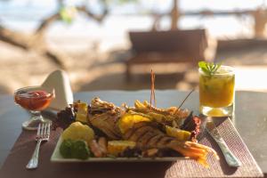 un piatto di cibo con carne e verdure e una bevanda di Los Vivos Beachfront Experience a Pochote