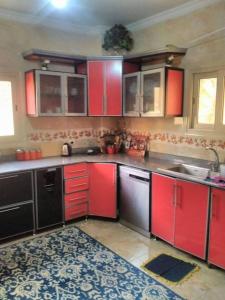 uma cozinha com armários vermelhos e um lavatório em فيلا مبهجة مع مسبح وحديقة رائعة em Cidade 6 de Outubro