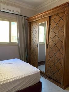 1 dormitorio con 1 cama y armario de madera en فيلا مبهجة مع مسبح وحديقة رائعة en 6th Of October