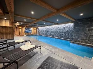 a swimming pool in a house with a stone wall at Chalet Les Belleville, 8 pièces, 15 personnes - FR-1-570-25 in Saint-Martin-de-Belleville