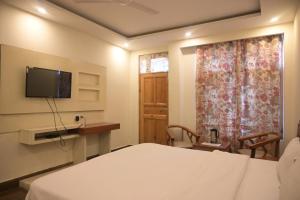 1 dormitorio con 1 cama y TV en la pared en Hotel Apple Blossom B$B en Manāli