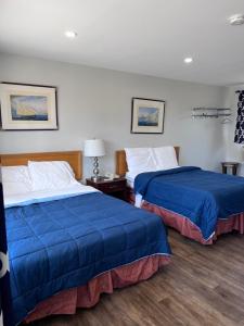 a hotel room with two beds with blue sheets at Knights Inn - Park Villa Motel, Midland in Midland