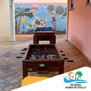 uma mesa de matraquilhos em frente a um mural em Pousada Mares de Stella em Salvador