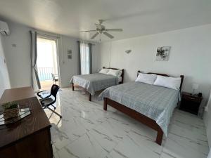 a bedroom with two beds and a desk and a ceiling fan at ElDorado Guesthouse in Roseau