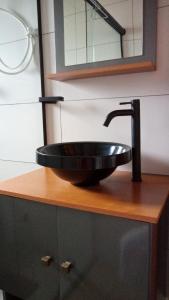 a black sink on a wooden counter with a mirror at Sonho na Serra Chalé 2 in Gonçalves