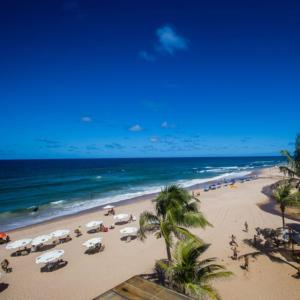 a beach with umbrellas and palm trees and the ocean at Pousada Mares de Stella in Salvador