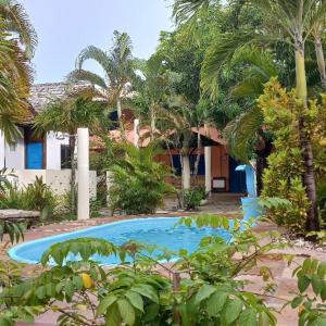 uma piscina em frente a uma casa com palmeiras em Pousada Mares de Stella em Salvador