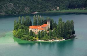 een huis op een eiland midden in een meer bij Apartments Zlatko in Jadrtovac