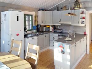 Holiday home Drangedal II في Drangedal: مطبخ فيه دواليب بيضاء وثلاجة بيضاء